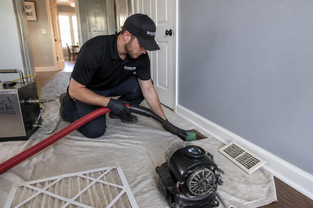 HVAC cleaning technician vacuuming and brushing a home air duct vent
